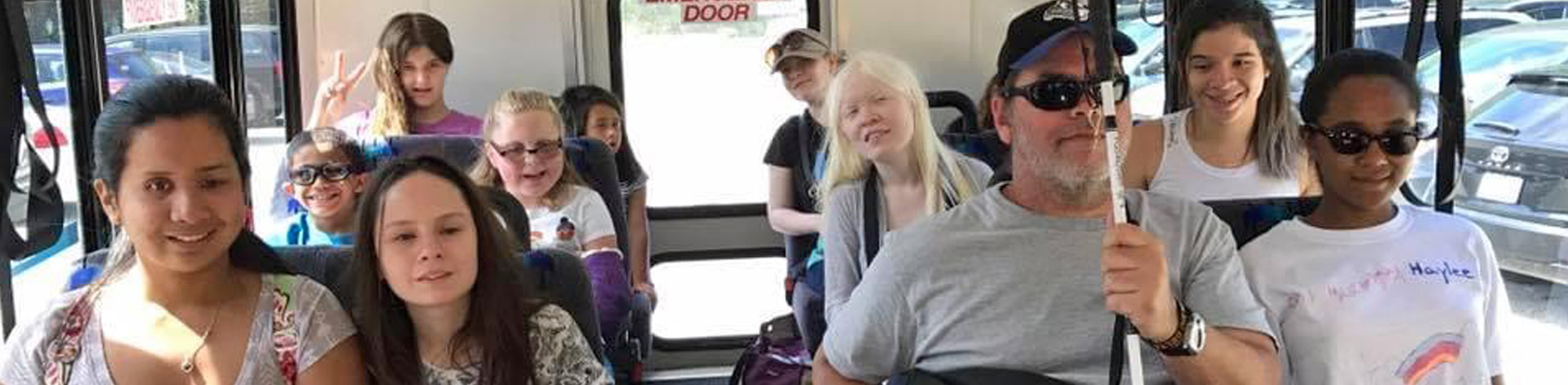 Blind students and mentors on a bus while out on a field trip.